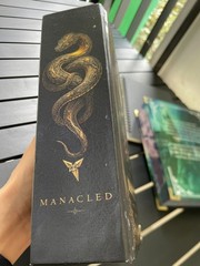 The limited edition hardcover novel Manacled (printed on three sides) collec